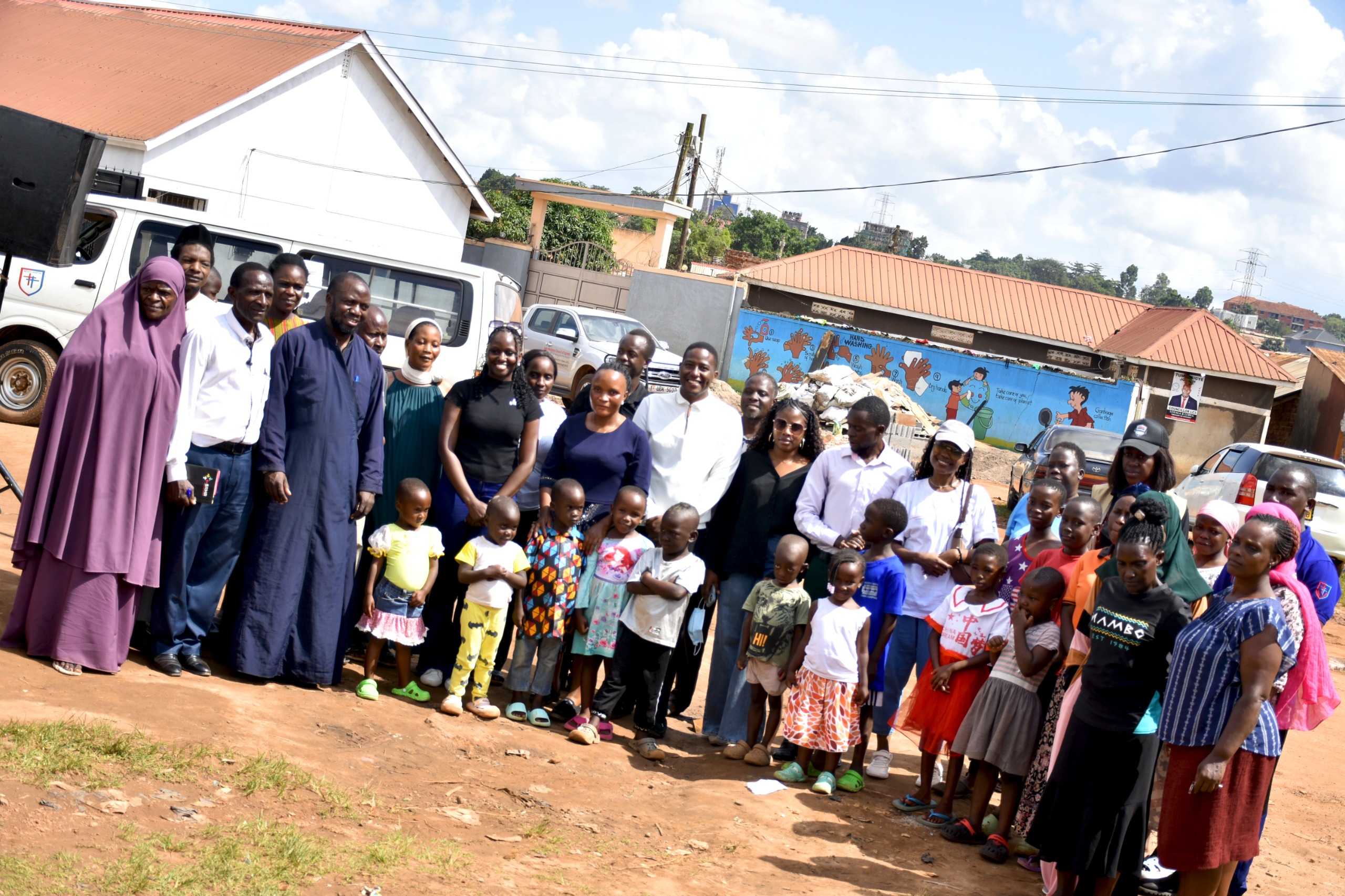 Some of the inter-faith youth take a photo with the community members after raising awareness on disease control in Kampala City.